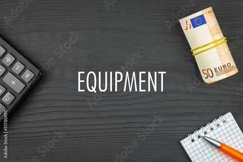 EQUIPMENT - word (text) and euro money on a wooden background, calculator, pen and notepad. Business concept (copy space).