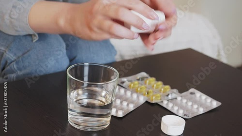 A young woman takes out a tablet, takes a glass of water and takes the medicine