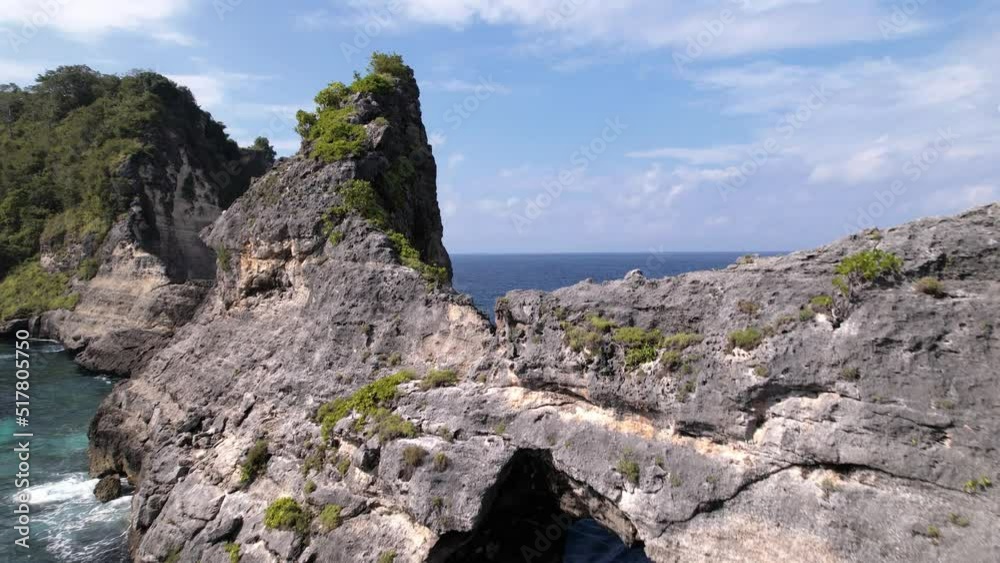 Aerial shot of rocky cliff. Indian ocean shore. Beautiful nature and travel summer vacation concept. Drone approaching to the island. Nusa Penida Island in Bali Aerial shot of rocky cliff. Indian ocean shore. Beautiful nature and travel summer vacation concept. Drone approaching to the island. Nusa Penida Island in Bali