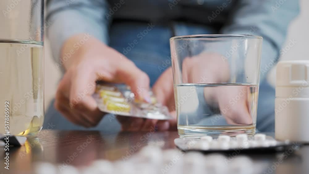 A young woman takes out a tablet, takes a glass of water and takes the medicine A young woman takes out a tablet, takes a glass of water and takes the medicine