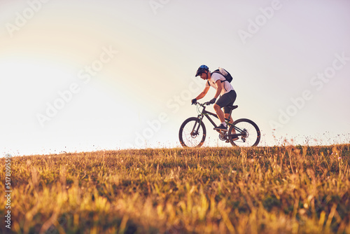 Tablou pe pânză A cyclist rides a bike on forest roads at sunset