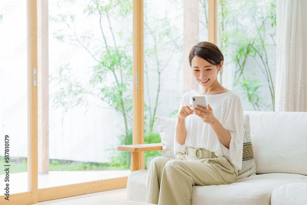 リビングでスマートフォンを使う女性 リビングでスマートフォンを使う女性