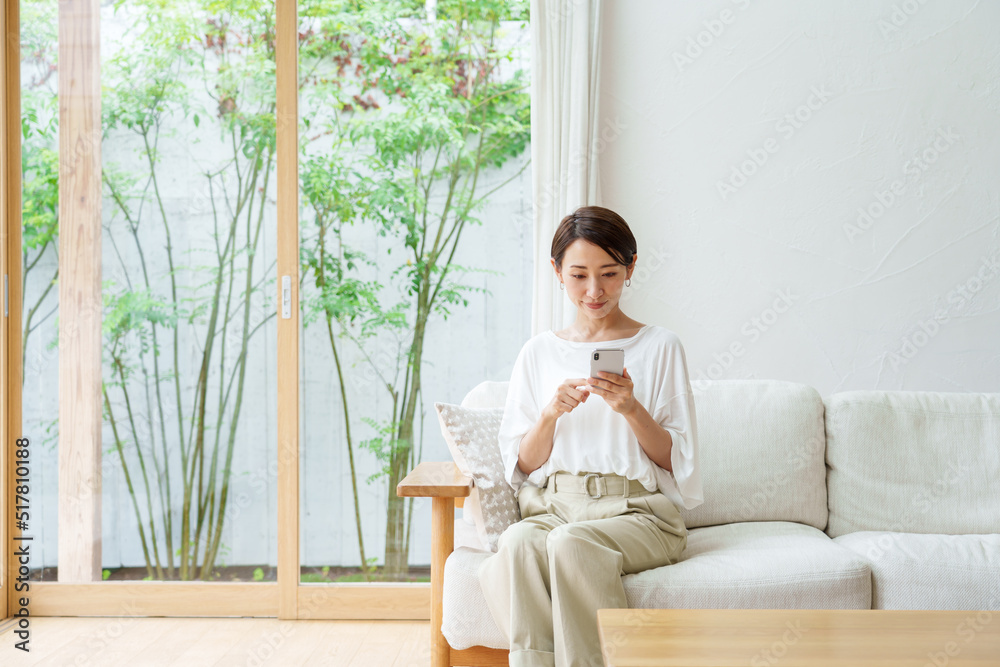 リビングでスマートフォンを使う女性 リビングでスマートフォンを使う女性