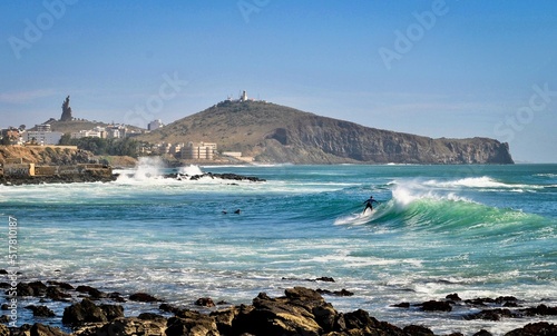 Un surfer prend une vague à Dakar, avec la colline des Mamelles en arrière-plan. photo