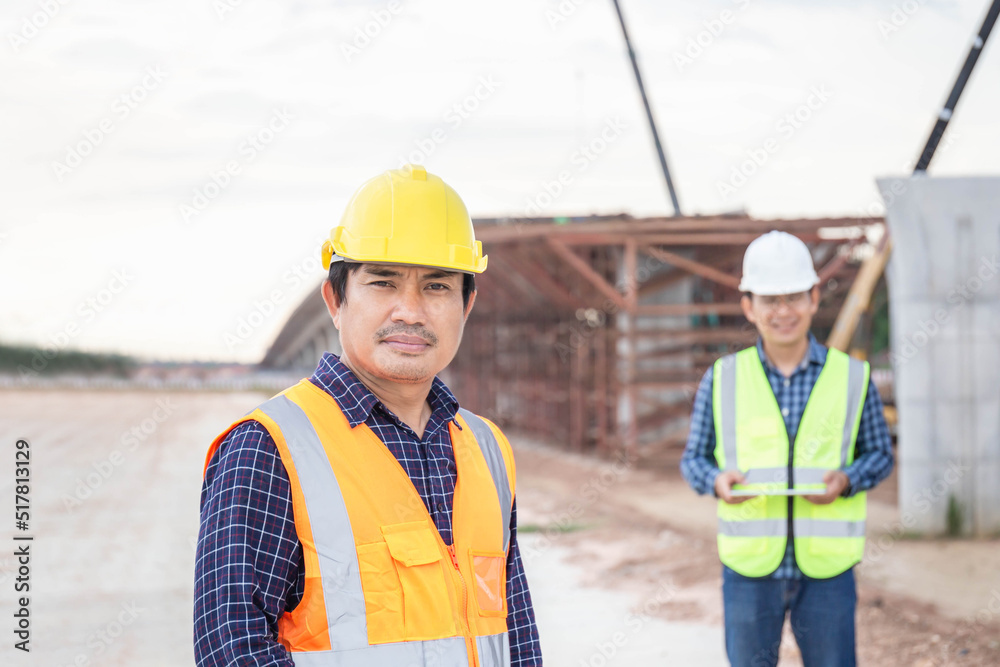 Engineer and foreman worker checking project at building site, Engineer and builders in hardhats in infrastructure construction site, Teamwork concepts Engineer and foreman worker checking project at building site, Engineer and builders in hardhats in infrastructure construction site, Teamwork concepts