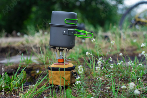 Tourist stove gas for camping and recreation on the background of a bicycle in nature.