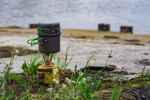 Tourist stove gas for camping and recreation against the backdrop of nature and the lake.