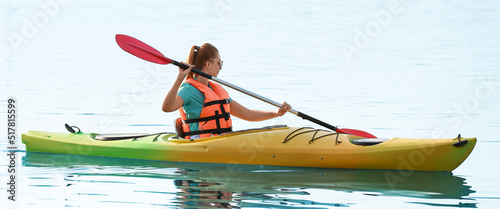 Young woman kayaking in river on summer day