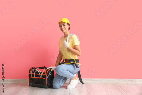 Female plumber with flexible hose near pink wall