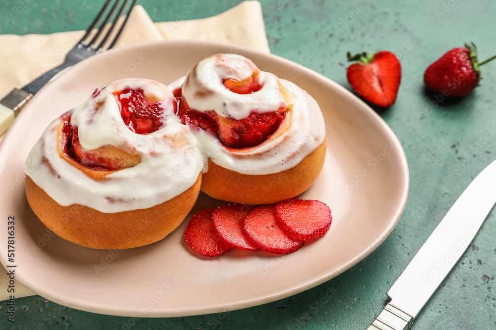 Plate with strawberry cinnamon rolls on green background, closeup Plate with strawberry cinnamon rolls on green background, closeup