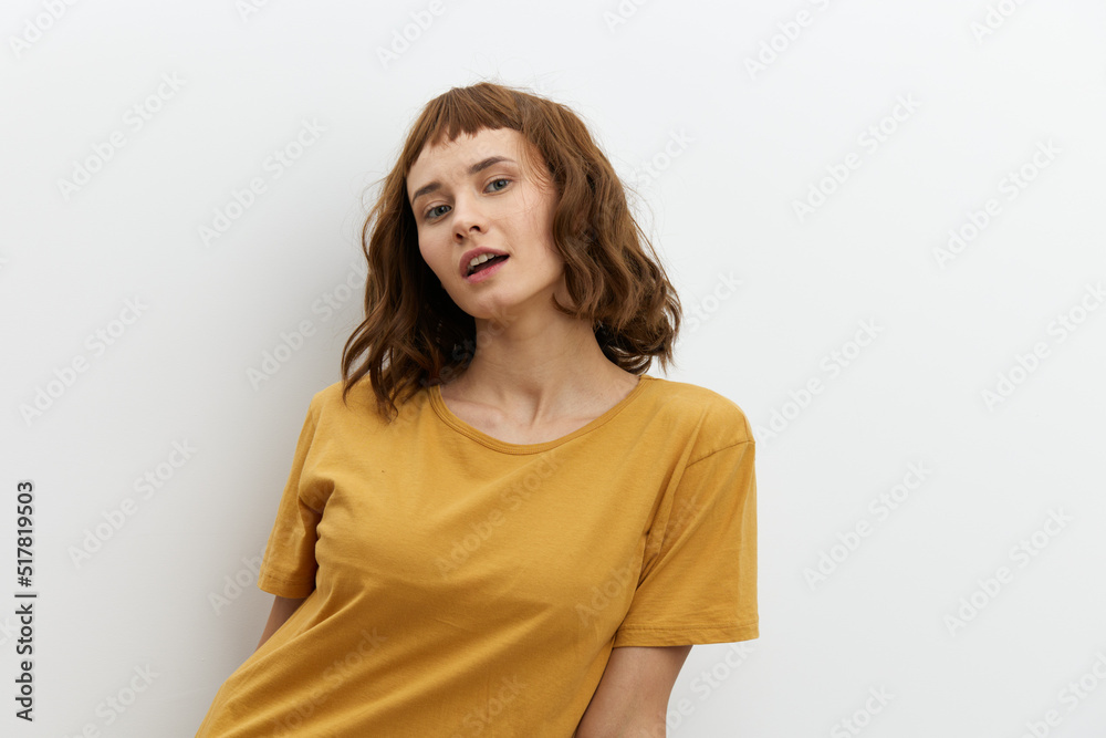 Obraz premium a sweet, beautiful, romantic woman in a yellow T-shirt poses on a white background, smiling pleasantly looking at the camera. Horizontal photo with an empty space for inserting an advertising layout