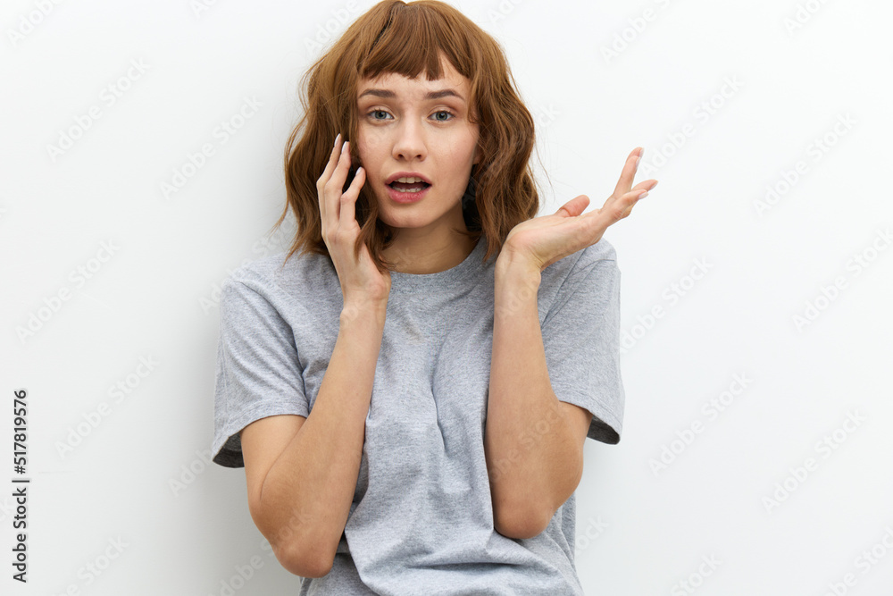 a funny, sweet woman stands in a gray T-shirt on a white background and spreads her arms wide, smiling a funny, sweet woman stands in a gray T-shirt on a white background and spreads her arms wide, smiling