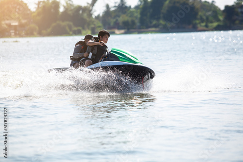 Asian teenager on jet ski with trainer. Teen age boy skiing on wave runner. Young man on personal watercraft in tropical sea. Jet ski training. Sport and ocean activity on beach holiday. photo