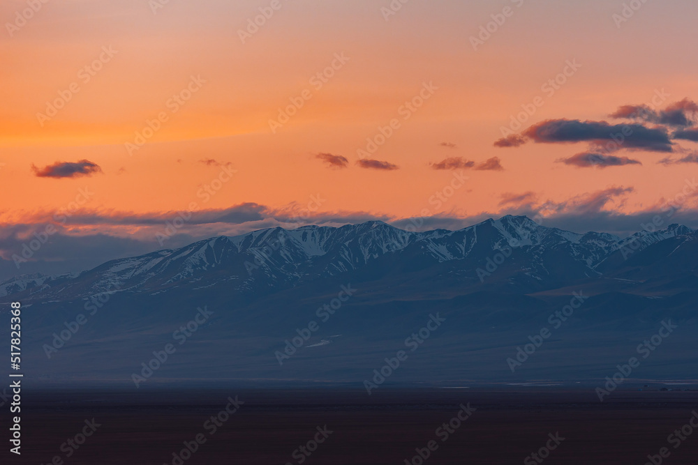 Red sunset with clouds in the Altai Mountains North Chuysky ridge, peaks with snow cover.