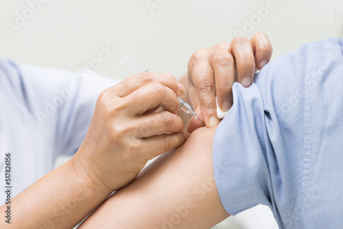 Close up doctor's hand injecting for vaccination in the shoulder woman patient.Vaccine for Covid19 or monkey pox.Vaccine for protection concept. photo
