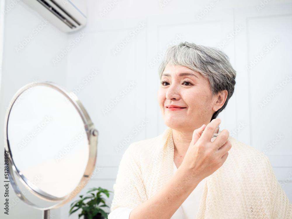 Portrait of mature aged asian woman 60s sprays perfume. Portrait of mature aged asian woman 60s sprays perfume.