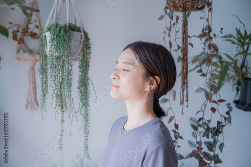 明るい植物のある室内で目を瞑るワンピース姿の日本人女性 photo