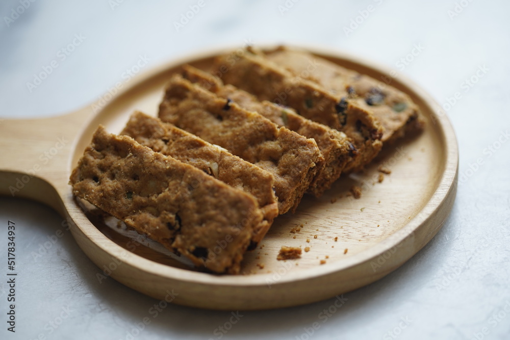 Healthy snack whole grains cookie crackers on a wooden plate white marble background rectangular shape closeup view