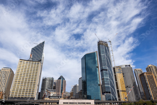 Modern glass skyscrapers rising above city under blue sky and clouds
