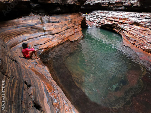 Australian woman sitting beside Kermits Pool Hancock Gorge in Karijini National Park Western Australia photo