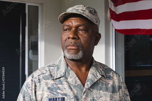 African american military senior man in camouflage clothing and cap looking away against house