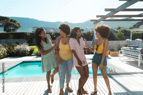 Carefree biracial female friends laughing and enjoying summer holiday at poolside, copy space © WavebreakMediaMicro