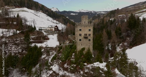 Superb orbit of the amazing Gernstein Castle, it is located over a hill in the Dolomites winter landscape photo