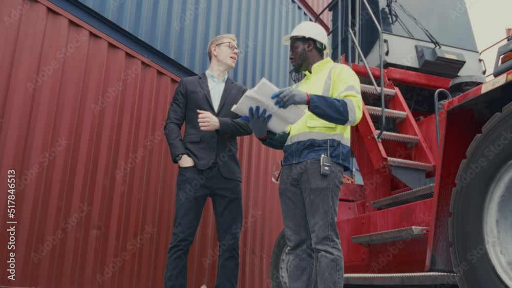 Low angle shot Business man and Industrial shipping worker discuss together at container yard. Logistics supply planning and management for international goods import export. Low angle shot Business man and Industrial shipping worker discuss together at container yard. Logistics supply planning and management for international goods import export.