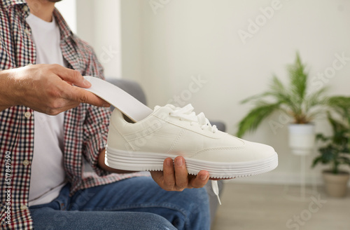 Young man puts new clean orthotic insole with foot arch support inside modern white comfortable orthopedic shoe he is holding in his hand Fototapet