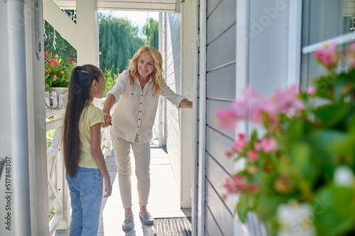 Mom and daughter stadnding near the house door