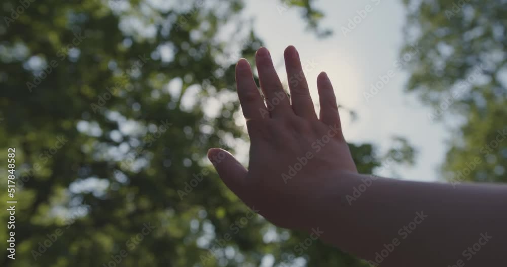 Caucasian woman closes the sun with her hand in slow motion in the park
