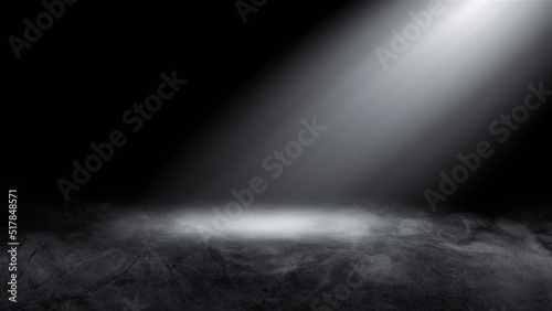 The empty space of the dark studio room, the concrete floor, the black background and the rays of light from the side illuminate the center.