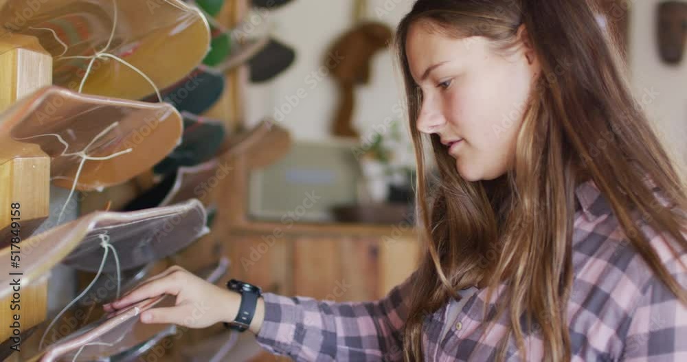 Video of caucasian female skateboarder searching for skateboard in skate shop