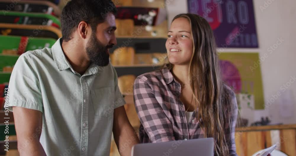 Video of diverse female and male skateboarders using laptop in skate shop Video of diverse female and male skateboarders using laptop in skate shop