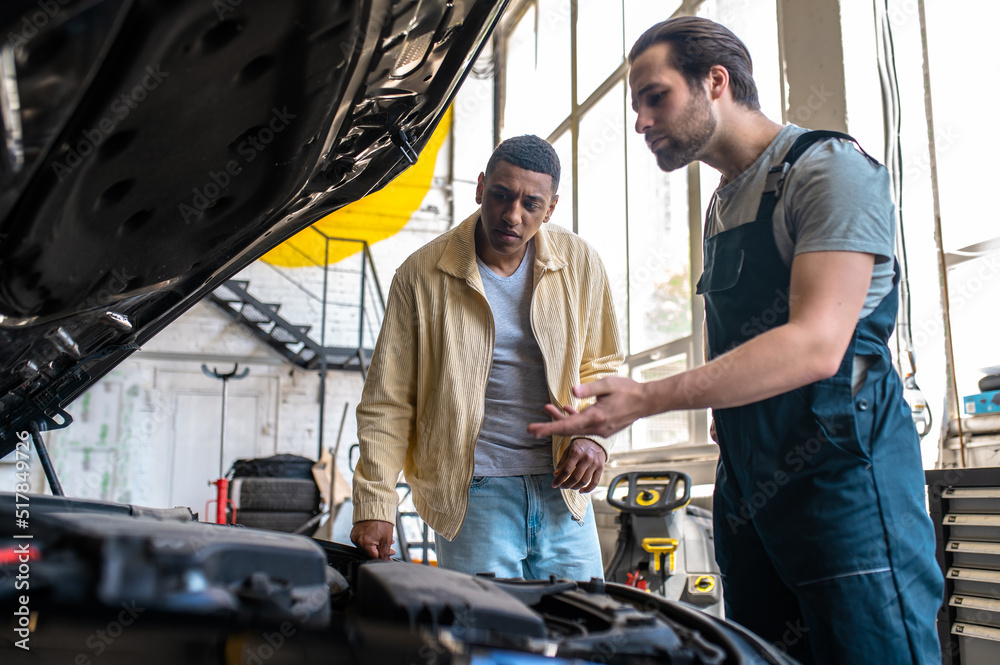 Technician in car service talking to the client Technician in car service talking to the client