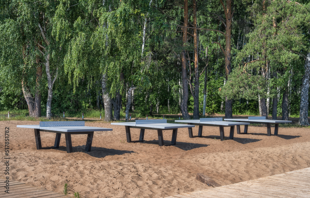 Tables for playing table tennis near the forest on the sand. River beach of Chaikovsky (Ural, Russia) in summer.