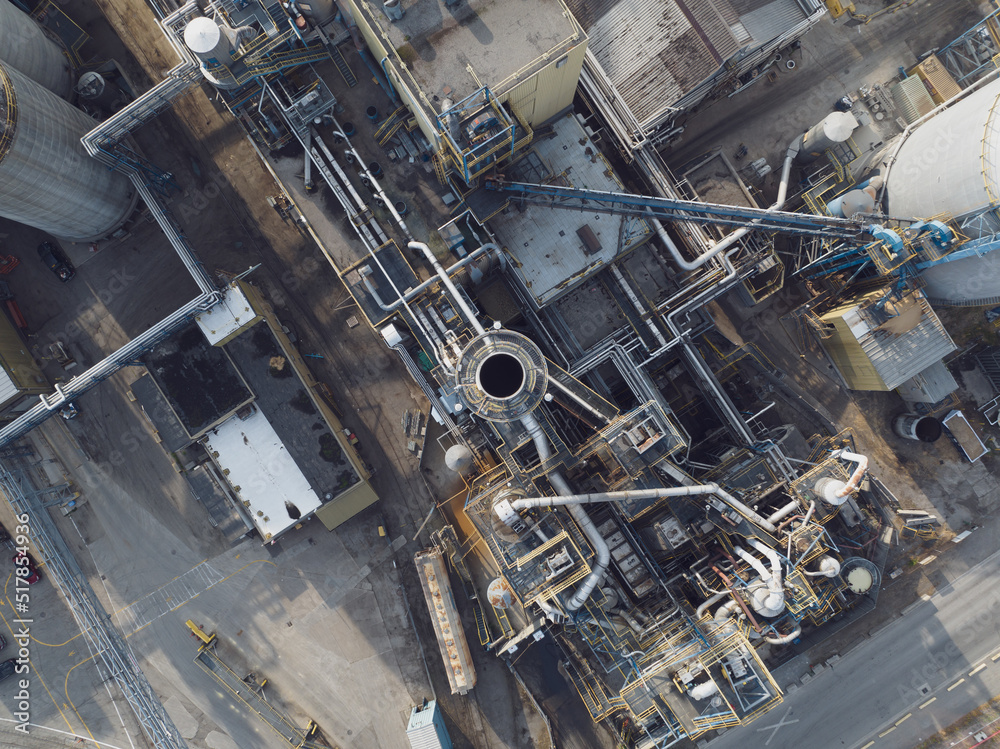 A closeup, aerial view direct on top of an industrial chimney or smokestack at a large manufacturing facility during a day.