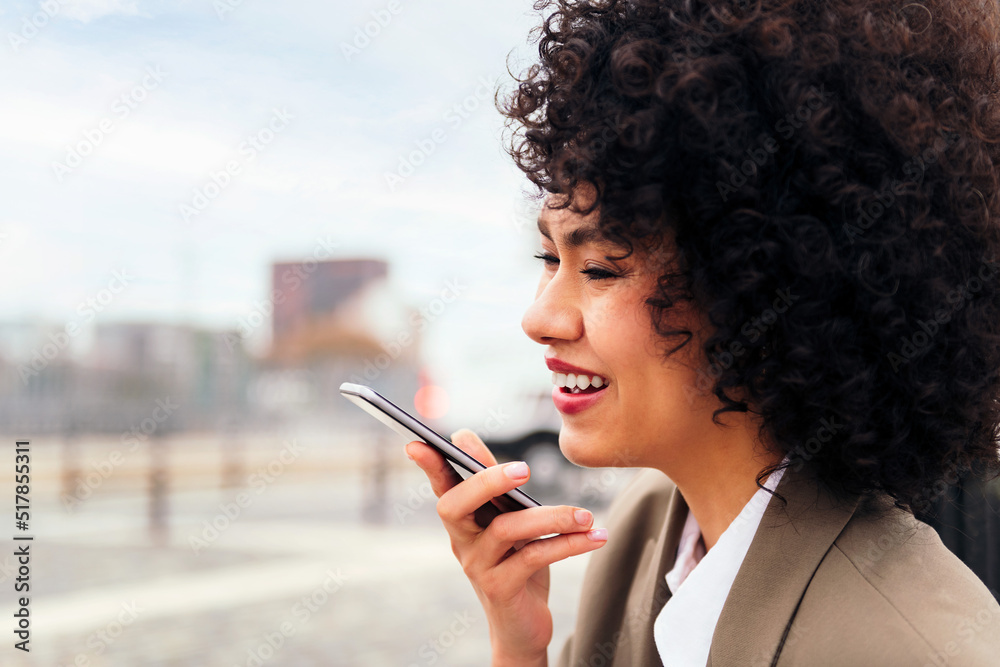 young latin woman smiles happy recording a voice message with a mobile phone, concept of communication and urban lifestyle, copy space for text young latin woman smiles happy recording a voice message with a mobile phone, concept of communication and urban lifestyle, copy space for text