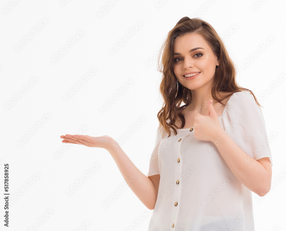 A young girl points her fingers at an empty space on a white background. A young girl points her fingers at an empty space on a white background.