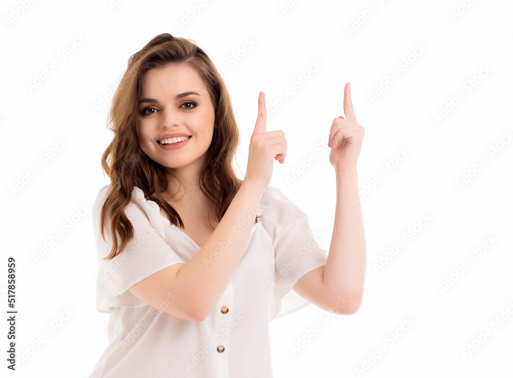 A young girl points her fingers at an empty space on a white background. A young girl points her fingers at an empty space on a white background.
