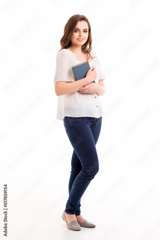 The girl stands on a white background with a book in her hands.