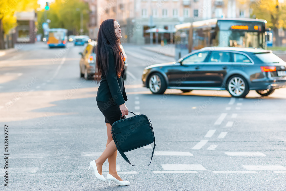 Young pretty business woman commuting and walking in city street with laptop bag.Side view,copy space.full-length. Young pretty business woman commuting and walking in city street with laptop bag.Side view,copy space.full-length.