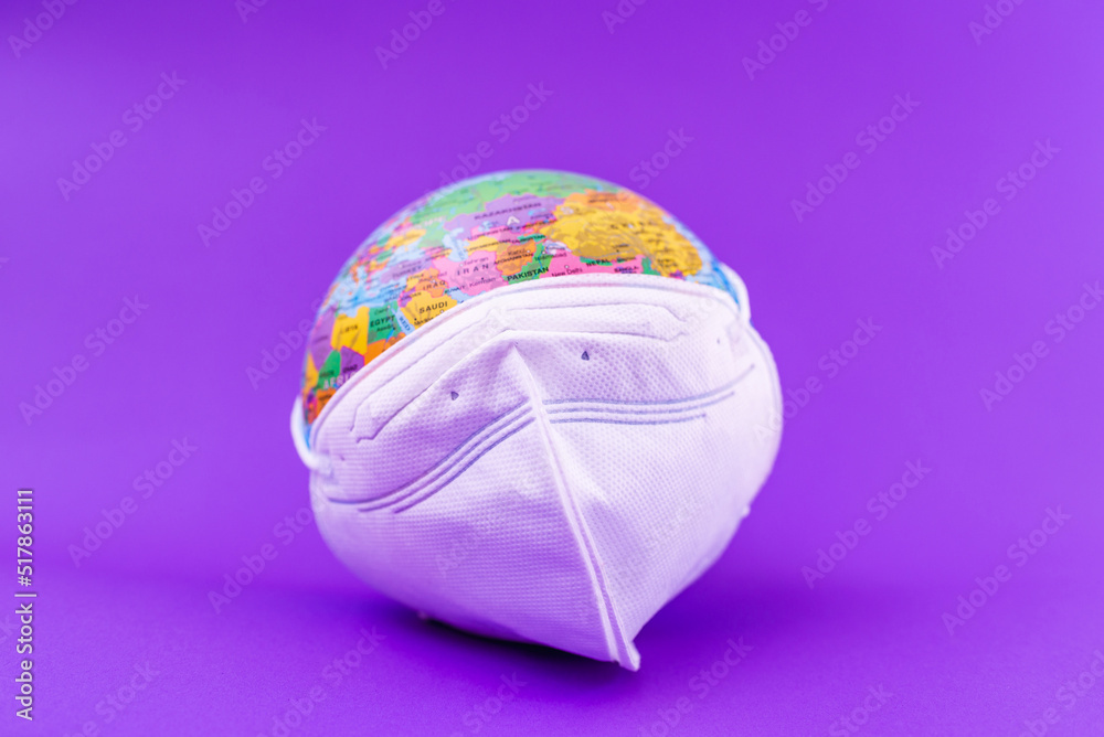 Fototapeta premium World Planet Earth with face mask protect flat lay on the purple ,veri peri background.World medical concept.