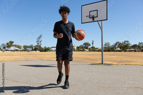 tall teenage basketball player on outdoor court with basketball photo