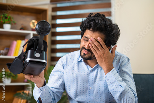 Foto young man rubbing his eyes after extensive use of VR or virtual reality goggles at office for meeting - concept of technology, metaverse and virtual meeting