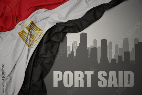 Vászonkép abstract silhouette of the city with text Port Said near waving colorful national flag of egypt on a gray background