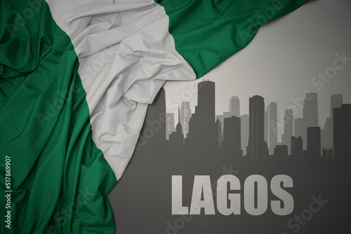 Cuadro en lienzo abstract silhouette of the city with text Lagos near waving colorful national flag of nigeria on a gray background
