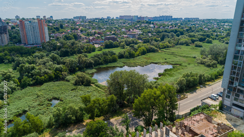 Drone aerial view marshy lake in the metropolis, summer nature in sunny day, green trees