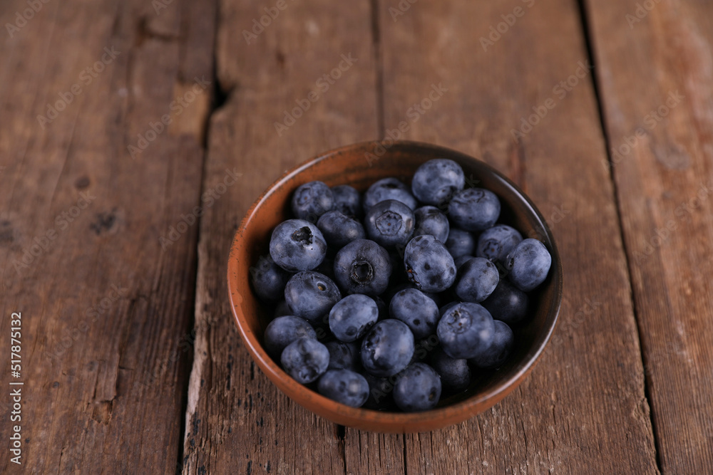 Fresh blueberries in a small bowl on a wooden table Fresh blueberries in a small bowl on a wooden table