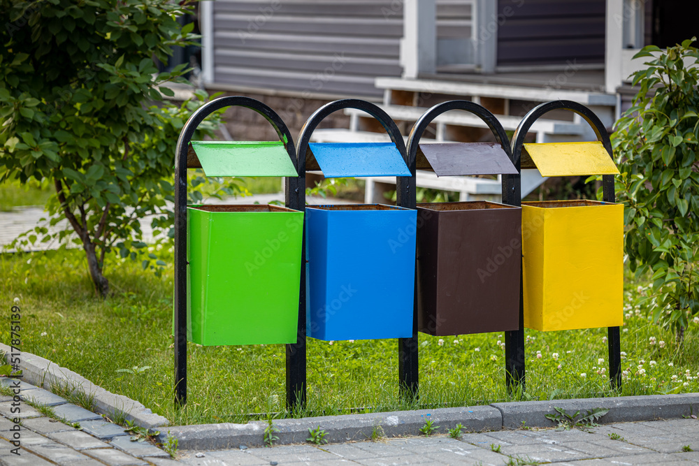 Naklejka premium small garbage containers of various colors stand in front of the house